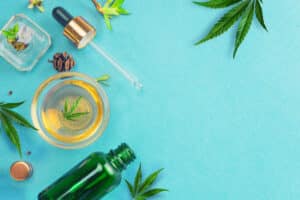 glass bottles with cbd oil, thc tincture and hemp leaves on blue background. flat lay, minimalism. cosmetics cbd hemp oil.